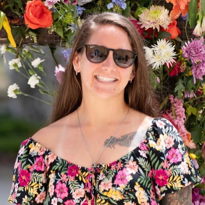 Coach Melana smiling in front of a wall of flowers